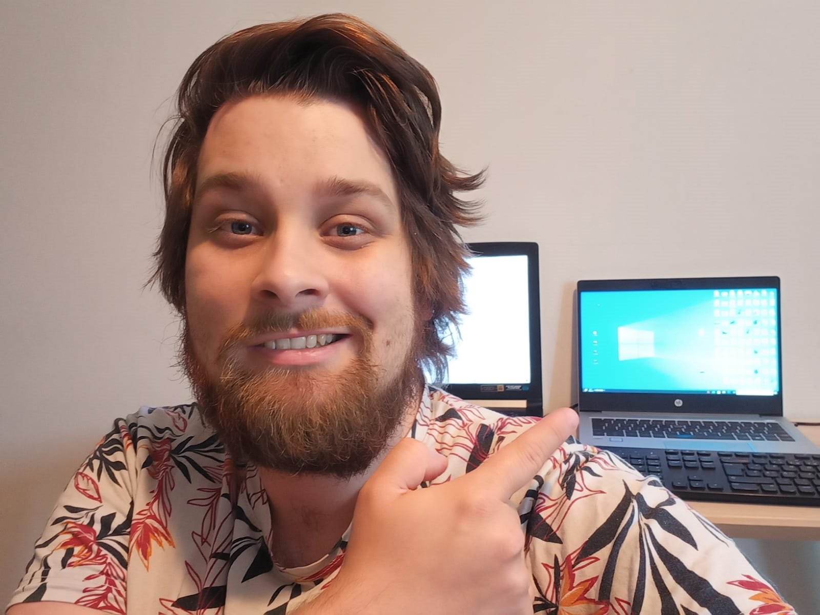 Rasmus Tillander hymyilee, takana kaksi avonaista tietokonetta.