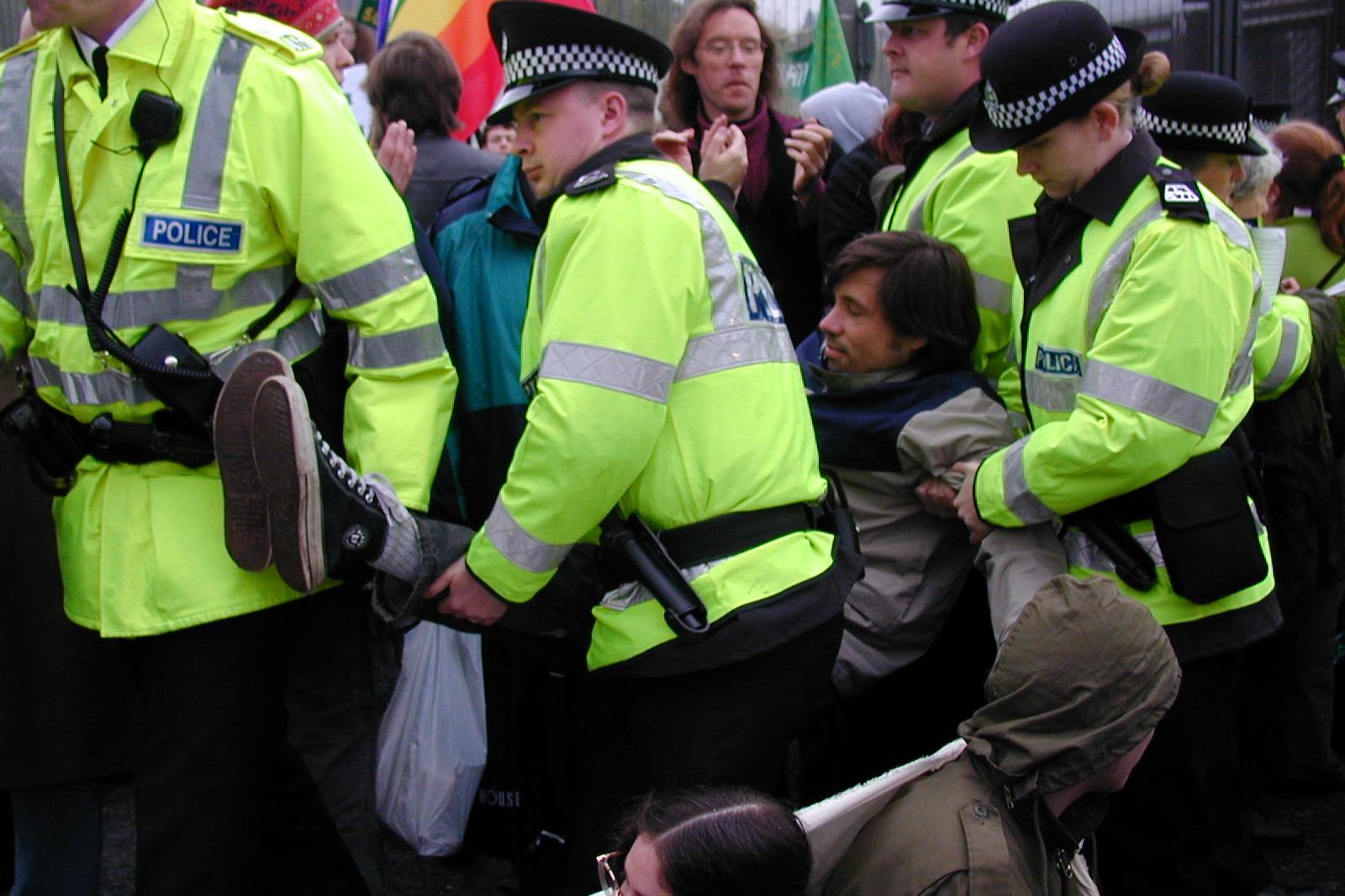 Poliisit kantavat mielenosoittaja pois Faslanen portilta.